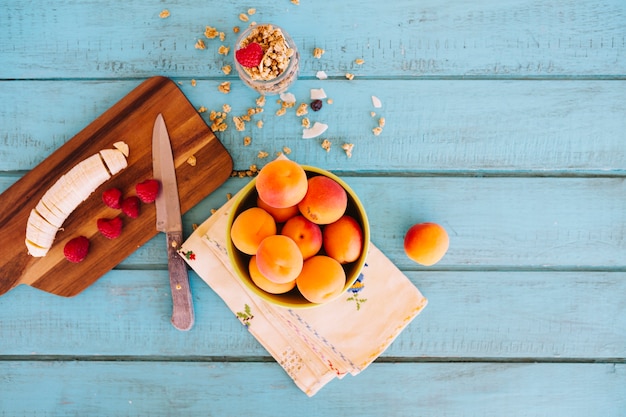 Fatias de banana; morangos; pêssego e aveia na mesa de madeira azul