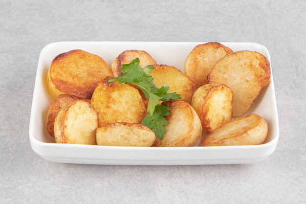 Fatias de batatas fritas na chapa branca.