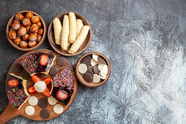 Fatias de bolo com nozes e biscoitos em superfície escura