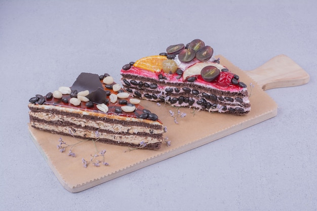 Fatias de bolo de chocolate em forma de triângulo com nozes e frutas em uma travessa de madeira