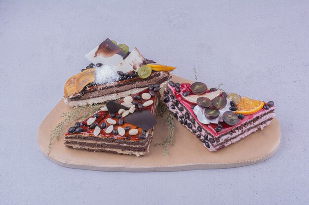 Fatias de bolo de chocolate em forma de triângulo com nozes e frutas em uma travessa de madeira