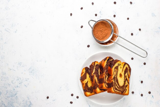 Fatias de bolo de mármore tradicional de passas com passas e cacau em pó, vista superior