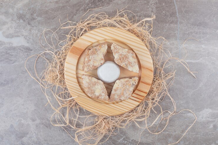 Foto grátis fatias de bolo em torno de um biscoito revestido de pó de baunilha em uma placa de madeira sobre mármore