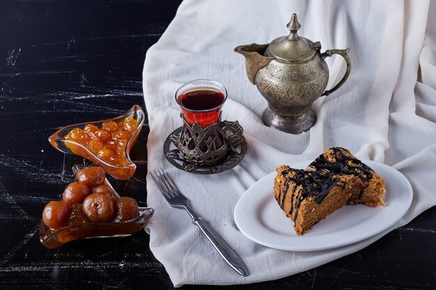 Fatias de bolo em um prato branco com calda de chocolate e chá.