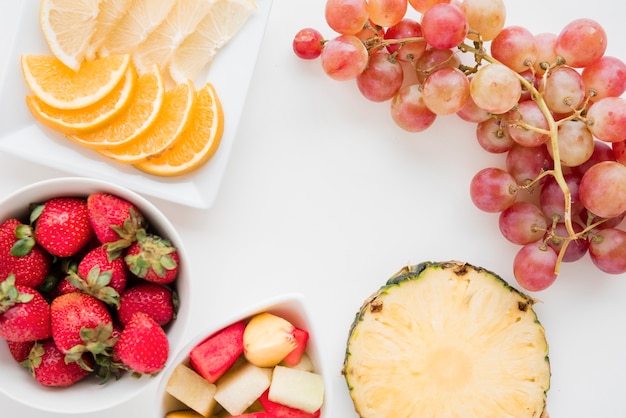 Fatias de frutas cítricas; morango; abacaxi; melancia e uvas no pano de fundo branco