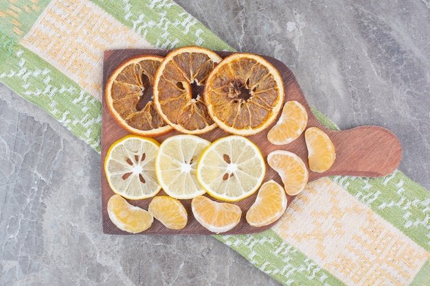 Foto grátis fatias de frutas cítricas na placa de madeira com toalha de mesa.