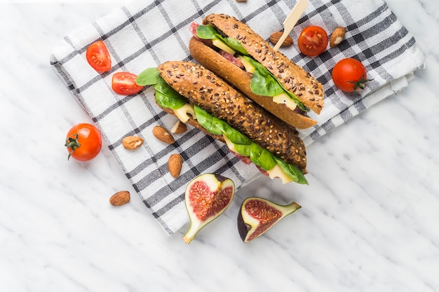 Fatias de frutas de figo; tomate cereja; amêndoas com cachorro-quente fresco sobre pano de cozinha em plano de fundo texturizado branco