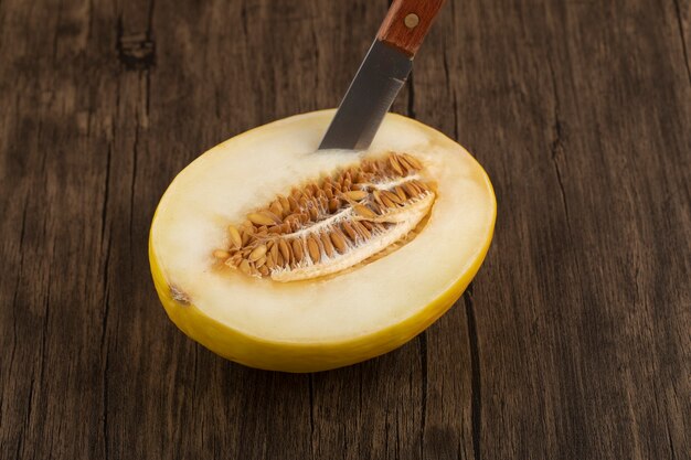 Fatias de frutas frescas de melão melão doce maduro com uma faca sobre uma mesa de madeira.