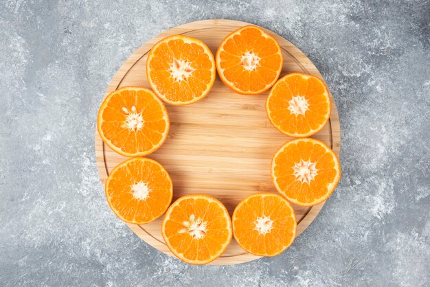 Foto grátis fatias de frutas suculentas de laranja frescas em uma placa de madeira.