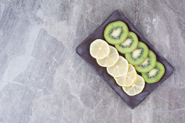 Foto grátis fatias de kiwi e limão na placa preta.