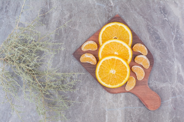 Fatias de laranja e tangerina na placa de madeira.