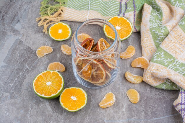 Fatias de laranja secas em frasco de vidro na superfície da pedra.