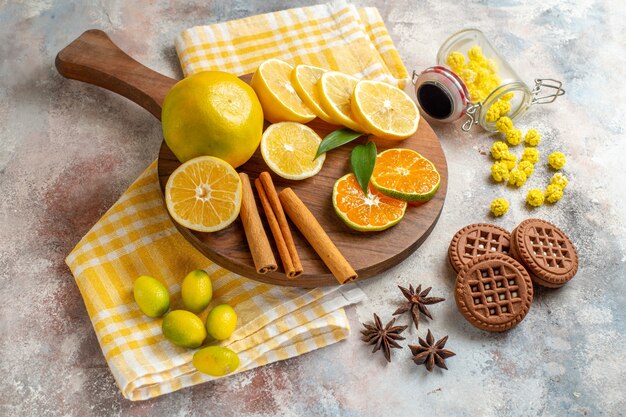 Fatias de limão, canela e limão em uma tábua de madeira e biscoitos na mesa branca