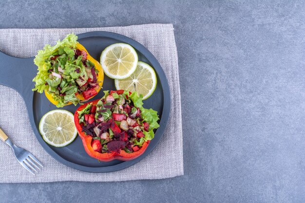 Fatias de limão com duas porções de saladas em rodelas de pimenta em uma travessa sobre superfície de mármore