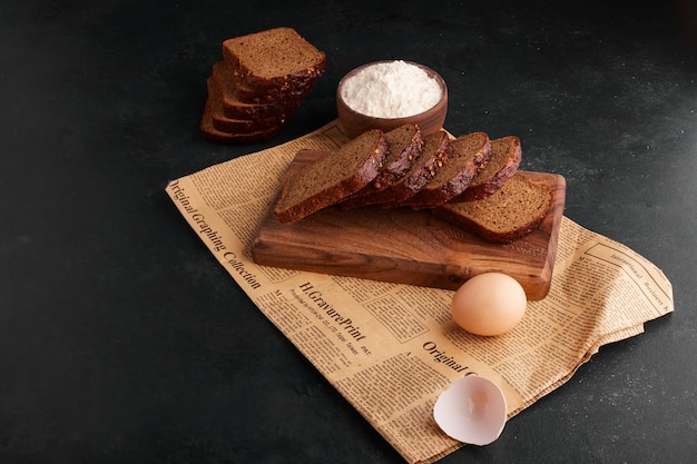 Foto grátis fatias de pão com ingredientes no pedaço de jornal.