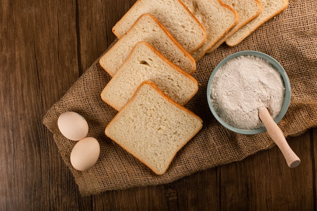 Fatias de pão com uma tigela de farinha e ovos