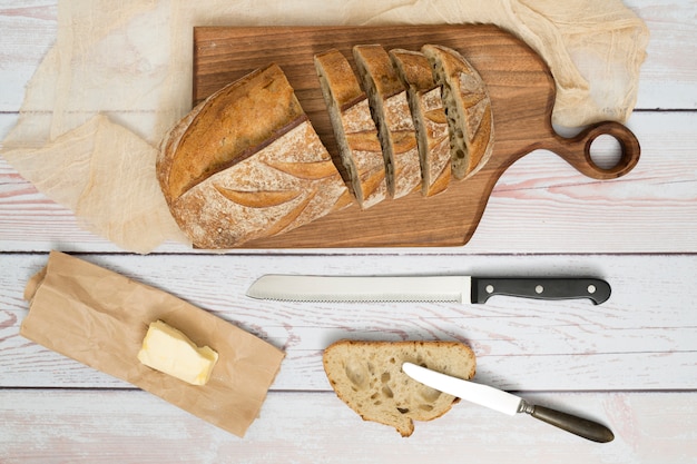 Fatias de pão; faca; manteiga no papel e butterknife na mesa de madeira