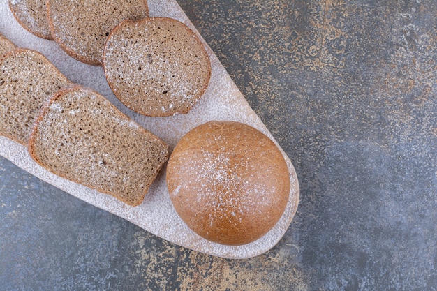 Foto grátis fatias de pão integral empacotadas em uma placa de madeira na superfície de mármore