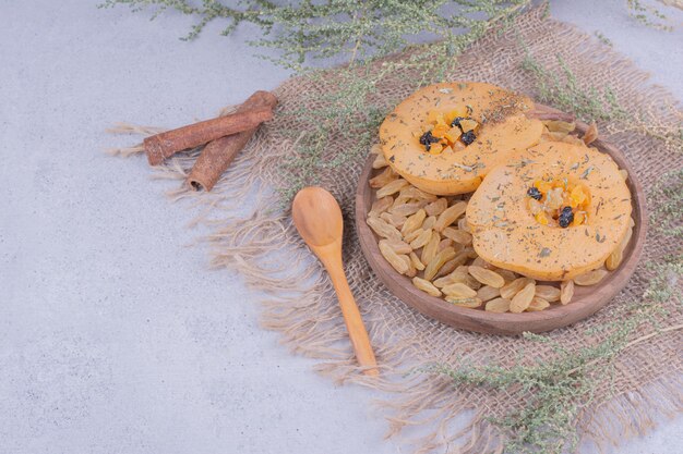 Fatias de pêra em um prato de madeira com sultanas e canela