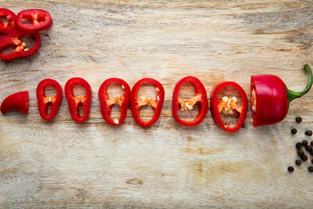 Fatias de pimenta vermelha com tempero de pimenta na mesa de madeira