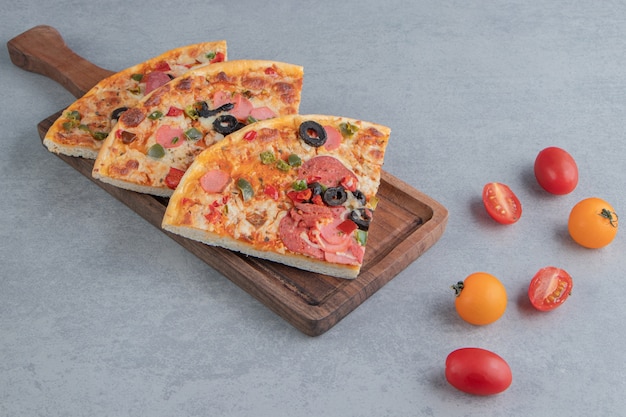 Fatias de pizza em uma bandeja ao lado de pequenos tomates no mármore