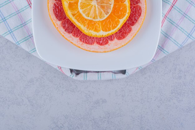 Foto grátis fatias de toranja fresca, laranja e limão na chapa branca.