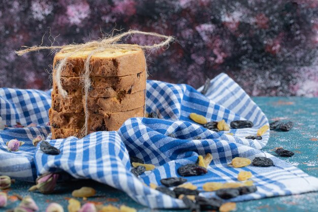 Fatias de torta com uvas secas em toalha xadrez azul.