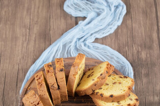 Fatias de torta macia com sultana preta na placa de madeira.