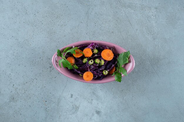 Fatias de vários vegetais e verduras em uma tigela rosa.