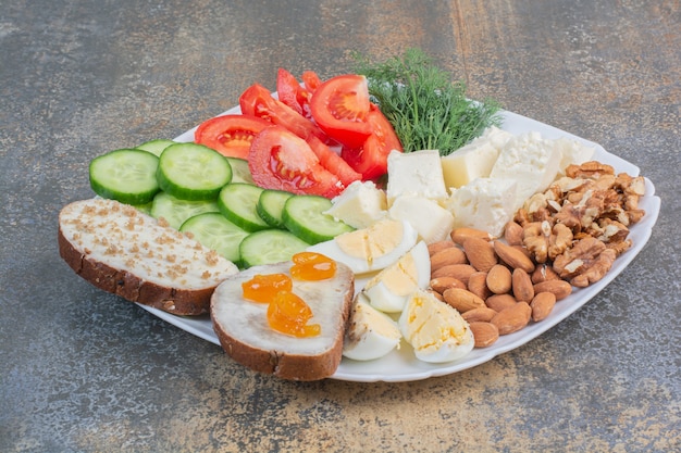 Foto grátis fatias de vegetais, ovos, queijo e nozes em prato branco