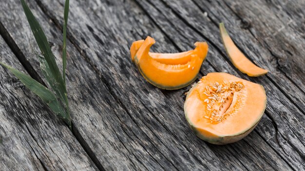 Fatias e metade de musk melon em um velho cenário de madeira