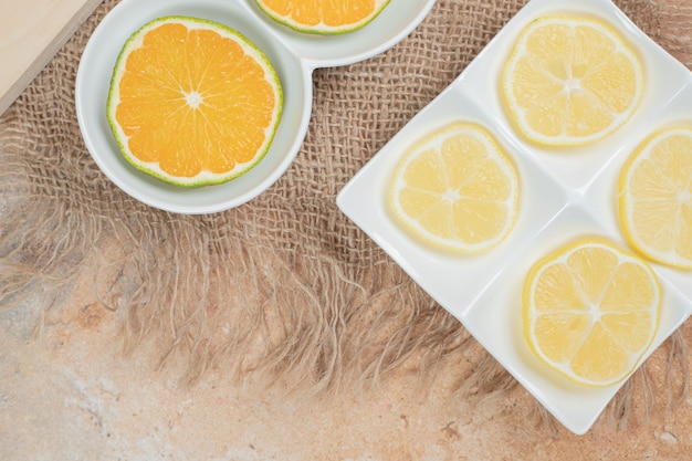 Fatias frescas de laranja e limão em vários pratos.