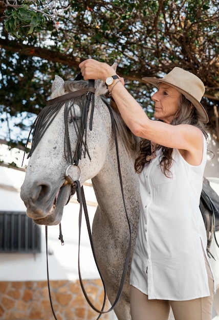 Foto grátis fazendeira equipando seu cavalo no rancho