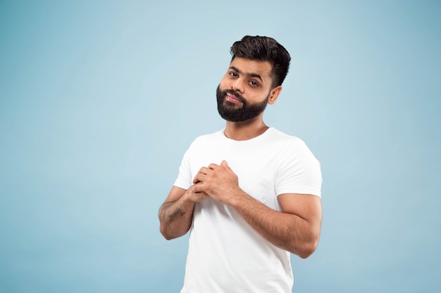 fechar o retrato de um jovem indiano de camisa branca. Posando, em pé e sorrindo, parece calmo.