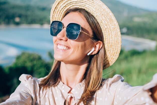 Fechar o retrato de uma jovem mulher com óculos escuros e brincos ao pôr do sol quente no parque