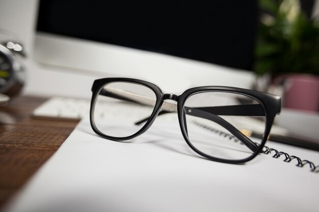 Fechar--se de óculos de leitura na mesa de escritório