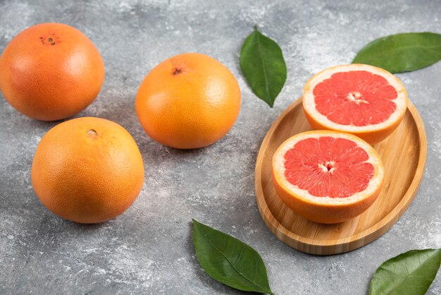 Feche a foto da toranja orgânica fresca e metade da toranja cortada na placa de madeira.