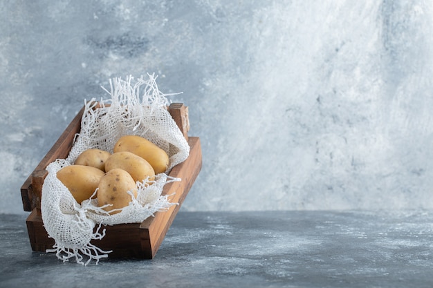 Foto grátis feche a foto de batatas maduras em uma cesta de madeira sobre um fundo cinza