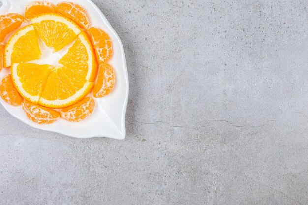 Feche a foto de fatias de laranja e tangerina na chapa branca.