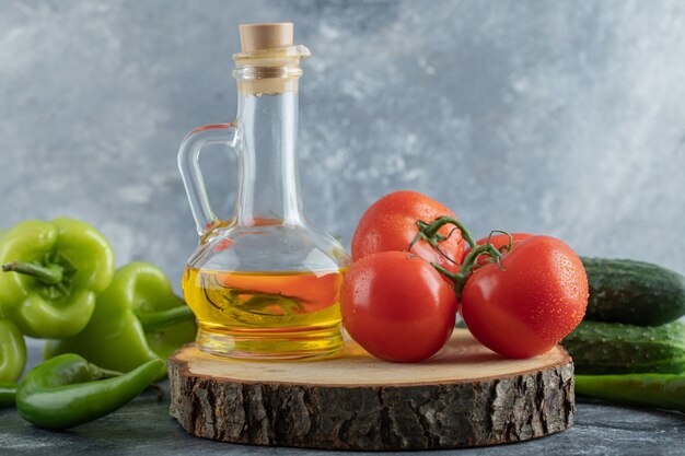 Feche a foto de tomate vermelho com pimentão verde e uma garrafa de óleo