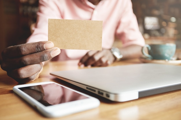 Feche a foto de um trabalhador corporativo africano mostrando um cartão de pergaminho em branco