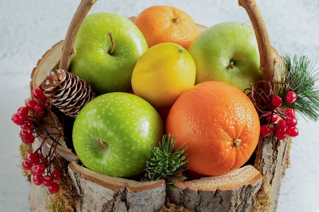 Feche a foto de uma cesta de madeira cheia de frutas diferentes.