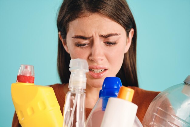 Feche a garota chateada olhando tristemente para resíduos plásticos sobre fundo colorido isolado