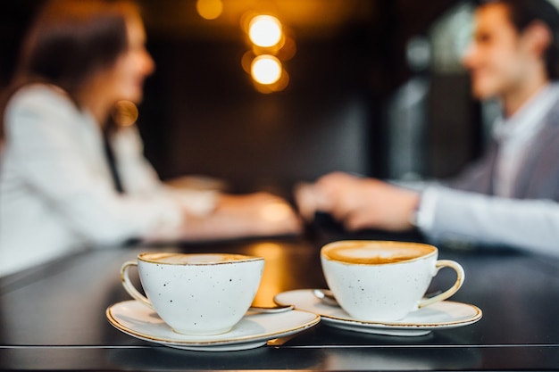 Foto grátis feche a imagem de duas xícaras de café com café com leite na mesa de madeira no café.