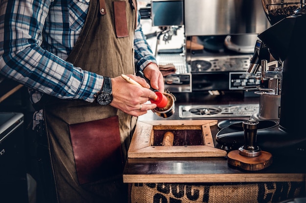 Feche a imagem de um homem limpa a máquina de café com uma borla.