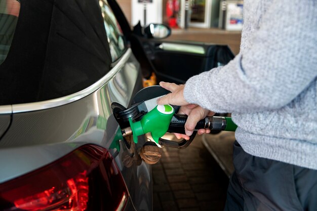 Feche a mão bombeando gasolina no carro