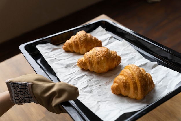 Foto grátis feche a mão com a bandeja de croissants