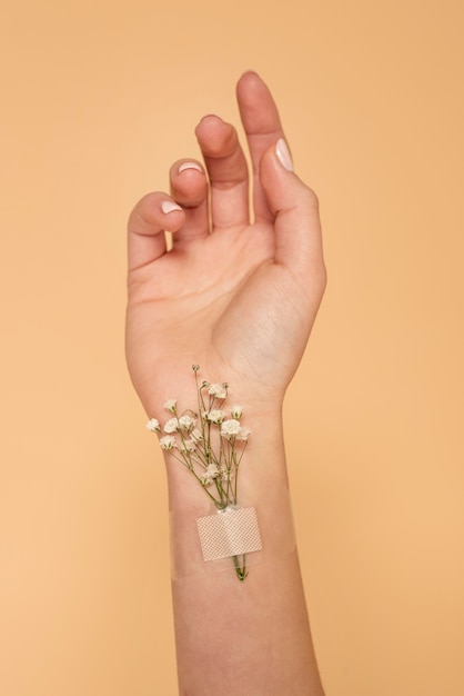 Foto grátis feche a mão com band-aid e flores