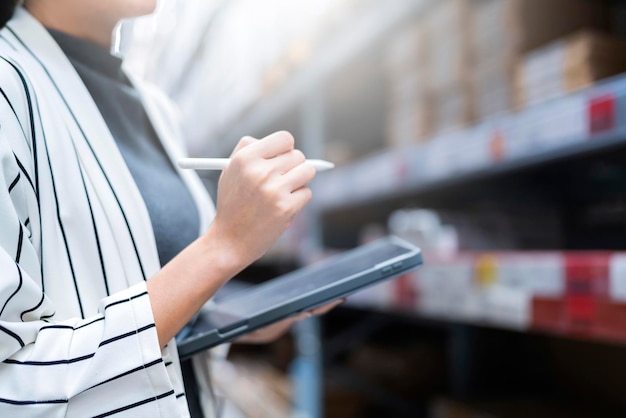 Feche a mão do proprietário da empresa feminina, segurando o tablet, verificando o estoque de estoque no conceito de ideias de negócios da fábrica do distribuidor do armazém da loja