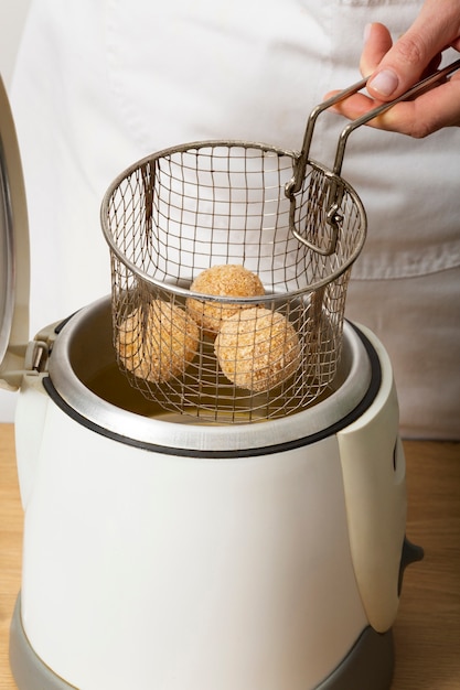 Feche a mão fritando croquetes de comida